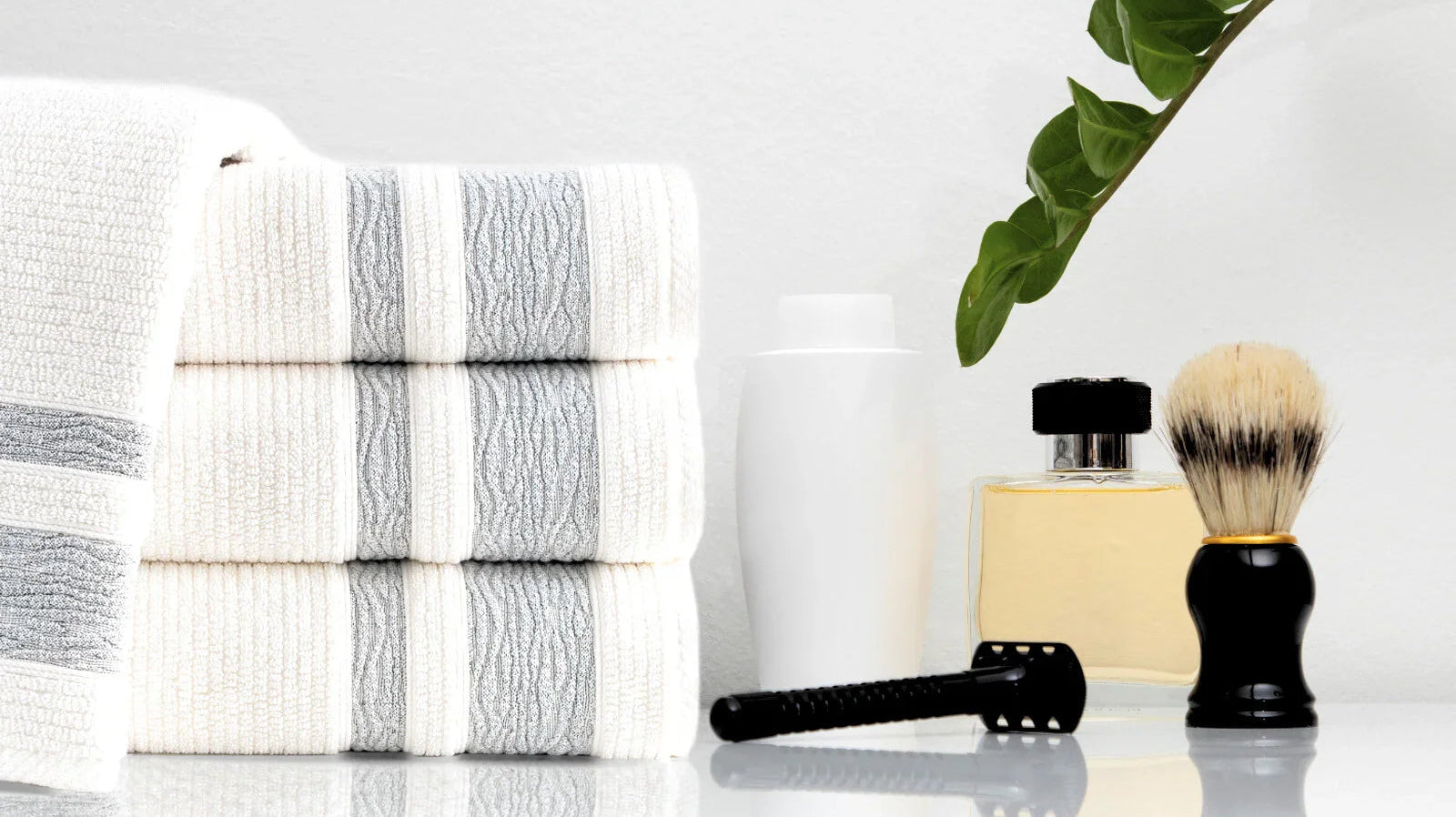 Stack of Turkish cotton towels with a razor, shaving brush, and toiletries on a bathroom counter.