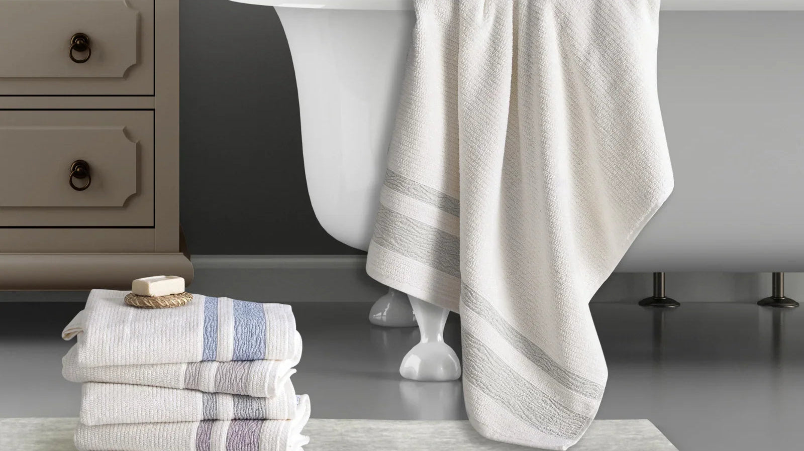 Stack of soft Turkish cotton towels and bath towel draped over a tub in a modern bathroom