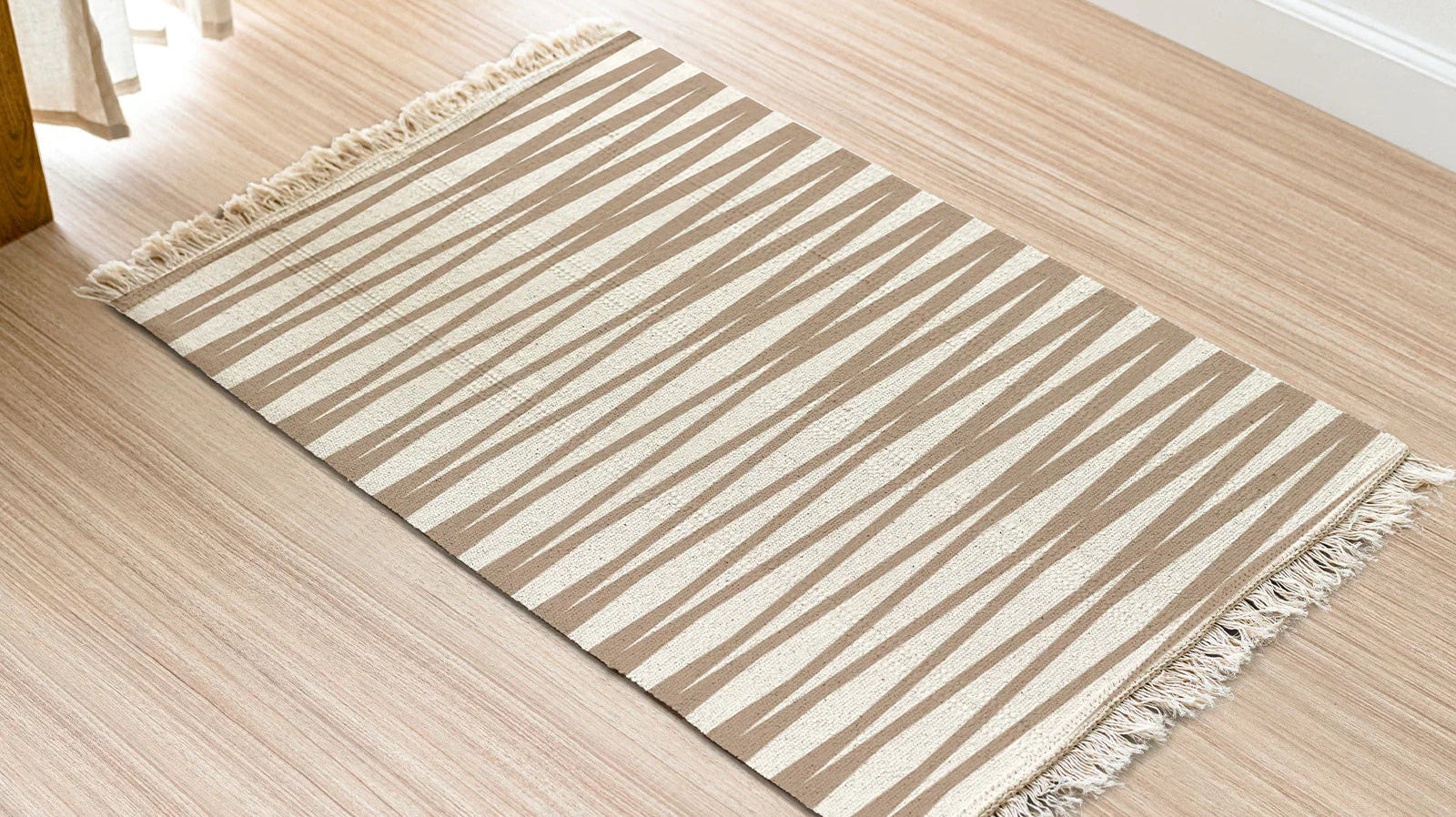 Beige and white striped hemp bathroom rug with fringed edges on light wood floor