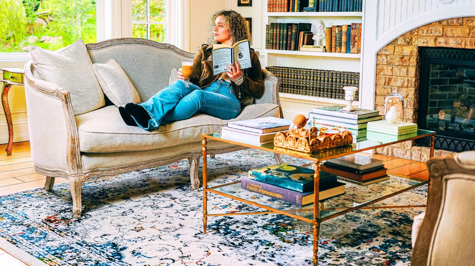 Cozy living room with blue patterned Turkish area rug, glass coffee table, and sofa by fireplace