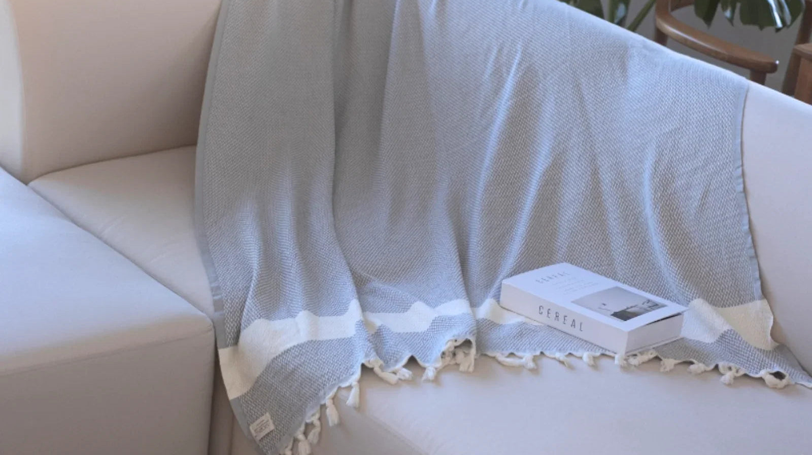 Light blue Turkish cotton throw blanket with white stripes draped over a cream sofa