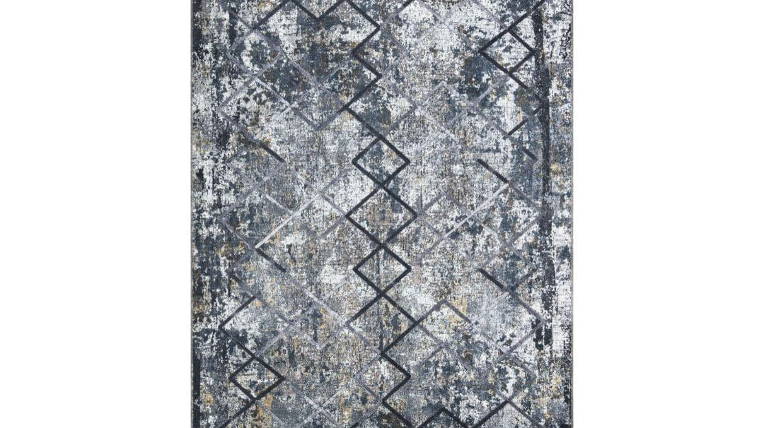 Low-pile geometric area rug layered over neutral carpet in a living room