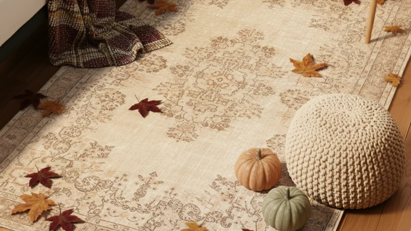 Vintage style Turkish area rug in cozy room with fall leaves, pumpkins, knit pouf, and blanket.