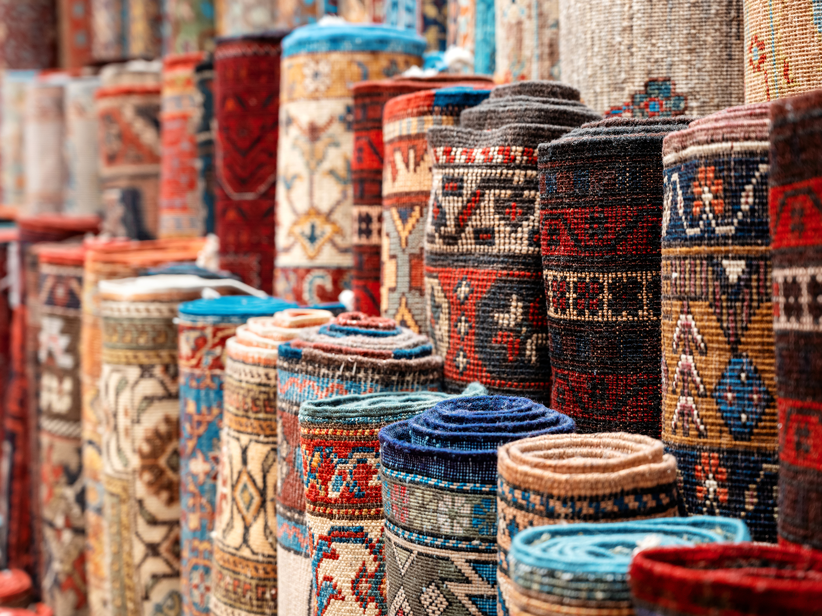 Rolled Turkish washable area rugs with colorful traditional patterns on display.