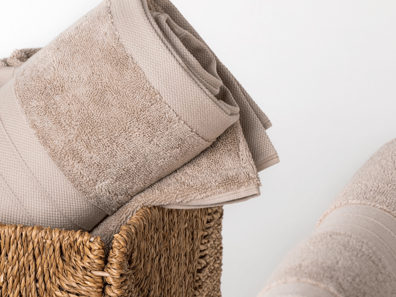 Beige Turkish cotton towels in a woven basket on a white background