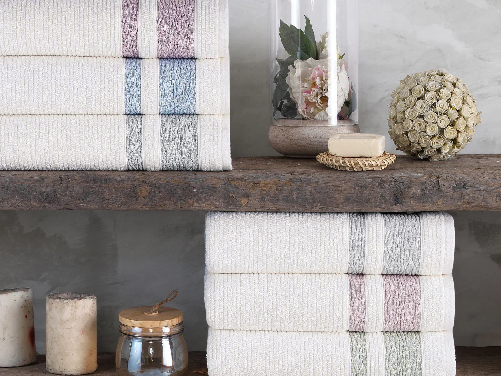 Stacked Turkish cotton towels with pastel stripes on wooden shelf, spa decor accents