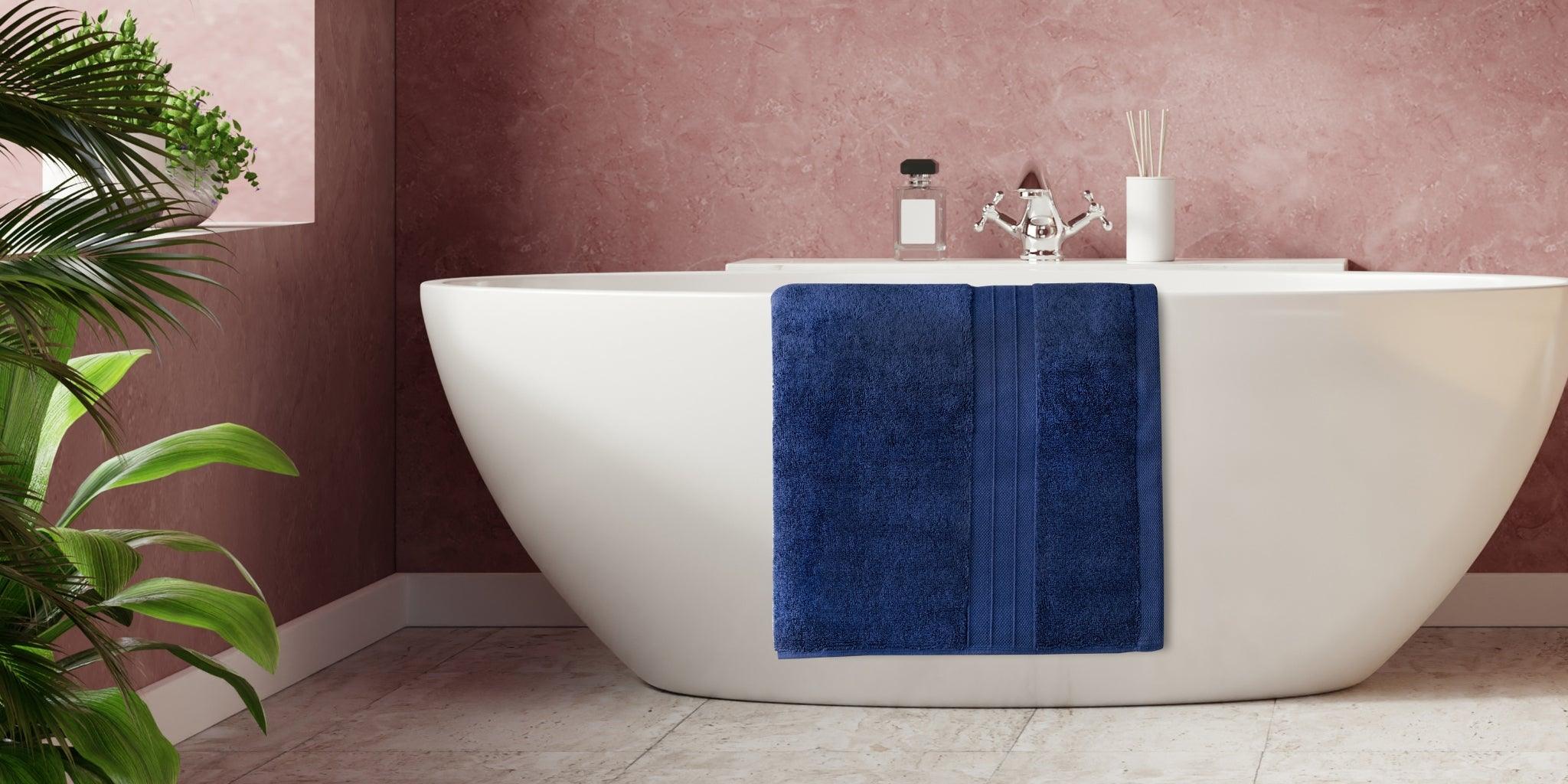 Navy blue Turkish cotton towel draped over modern white bathtub in stylish bathroom
