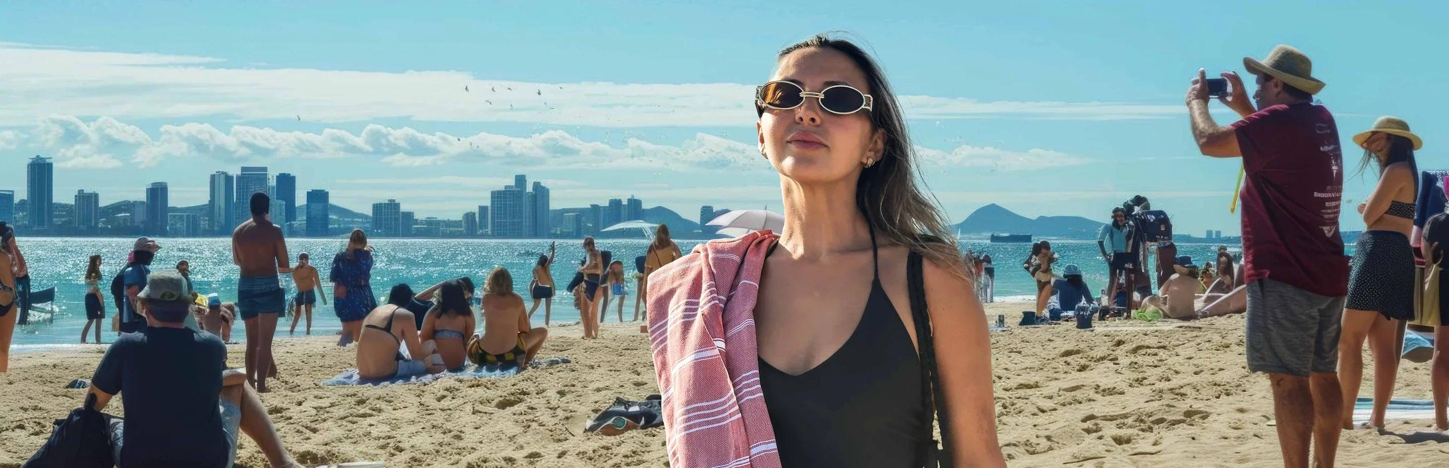 Woman with Turkish cotton beach towel on shoulder standing on sunny city beach