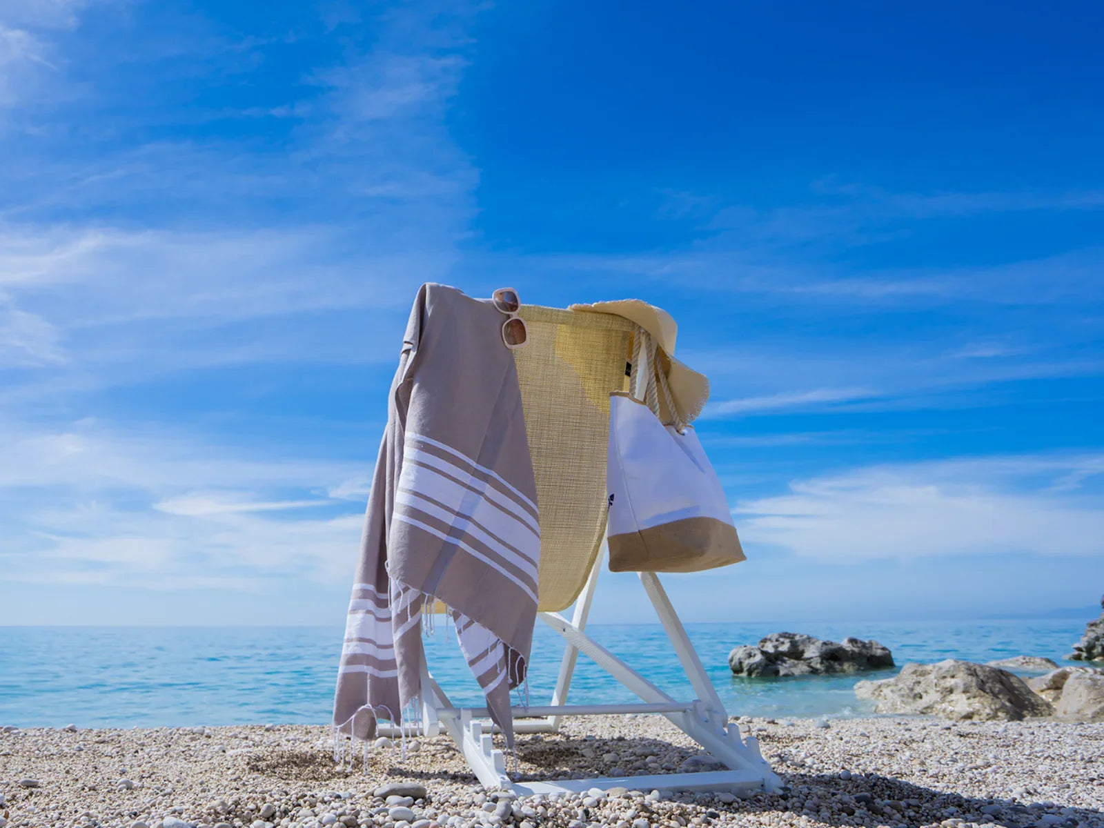 Turkish cotton towel draped on a beach chair with sunhat and bag by the seaside