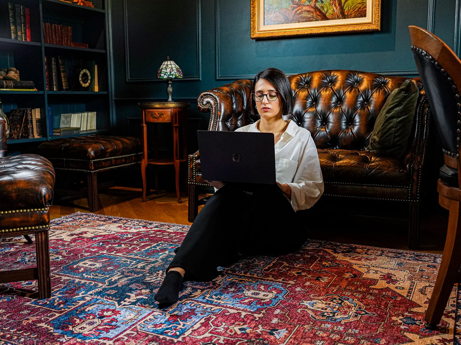 Woman using laptop on red Turkish washable area rug in cozy vintage living room