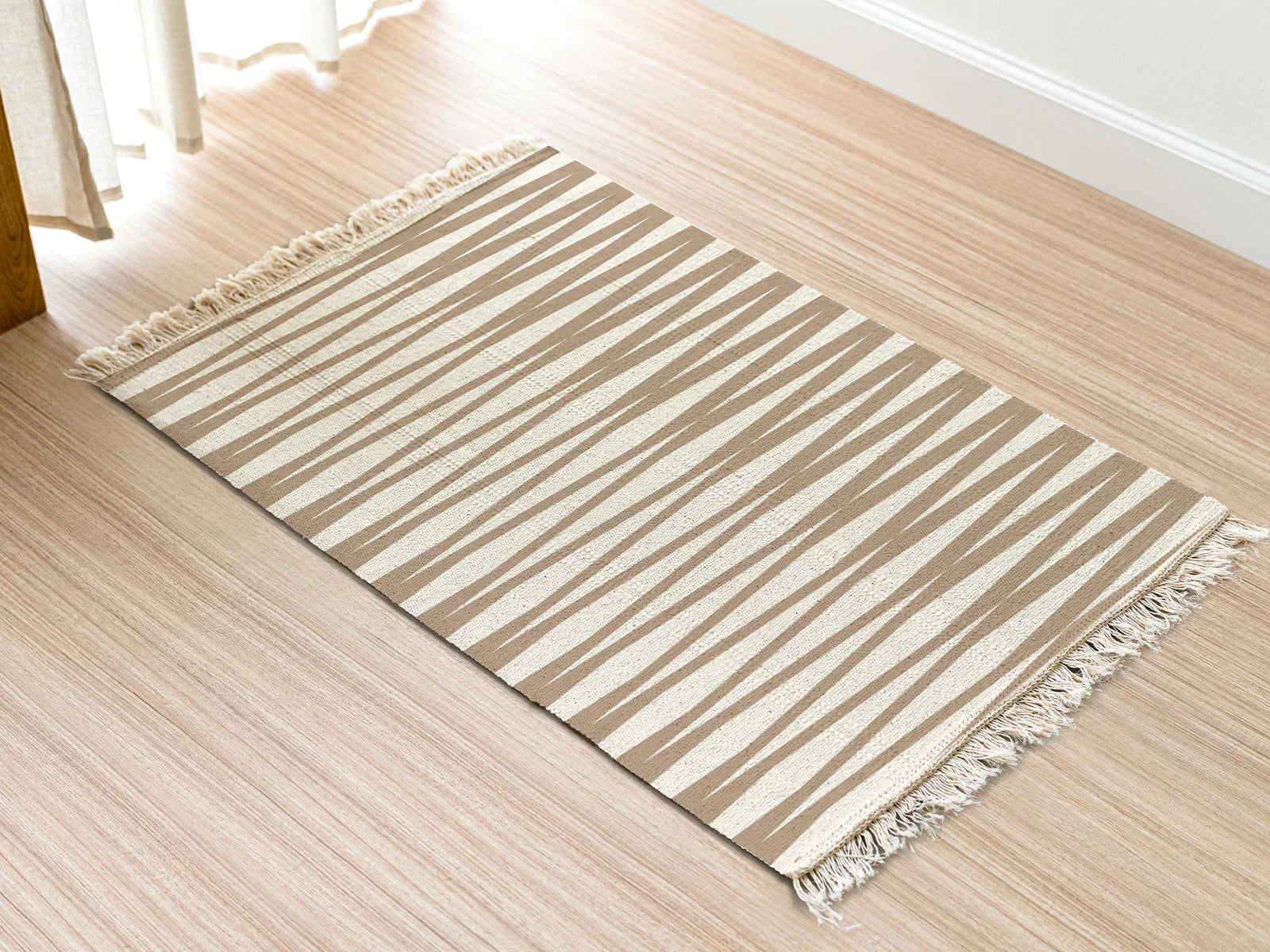 Beige and white striped hemp bathroom rug with fringed edges on light wood floor