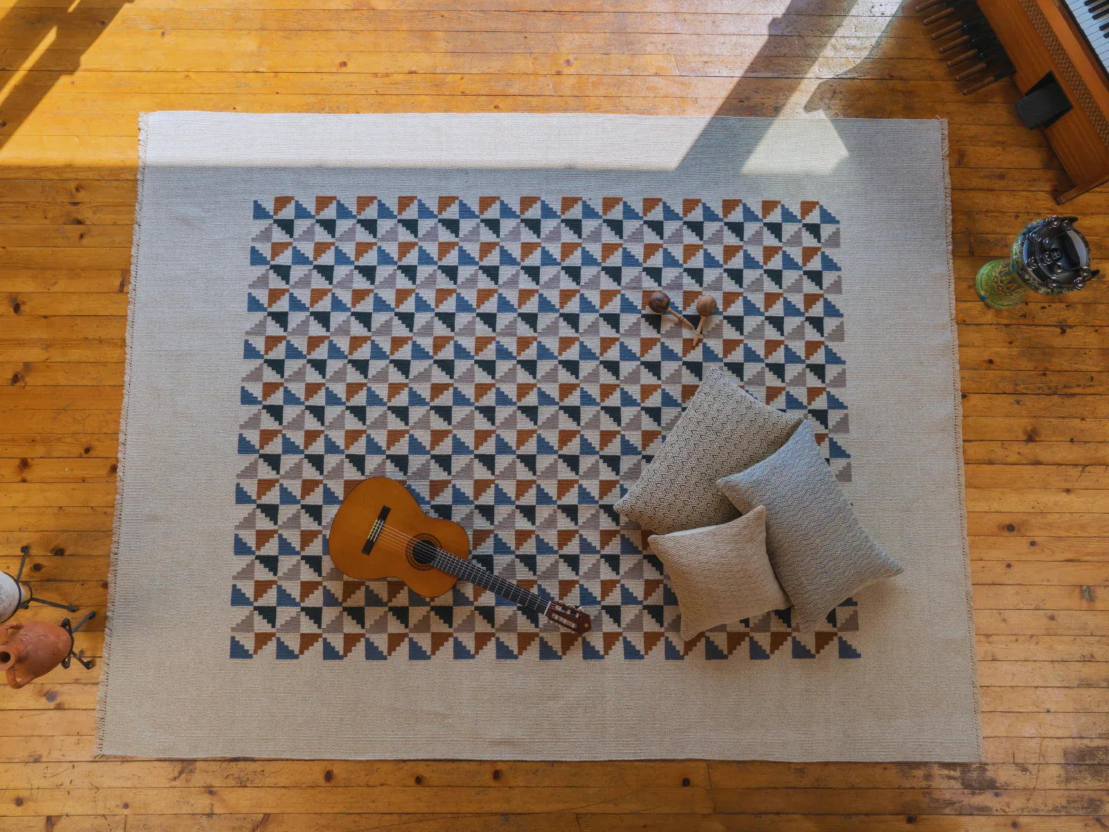 Hand-woven Turkish area rug with geometric pattern, pillows, and guitar on wooden floor