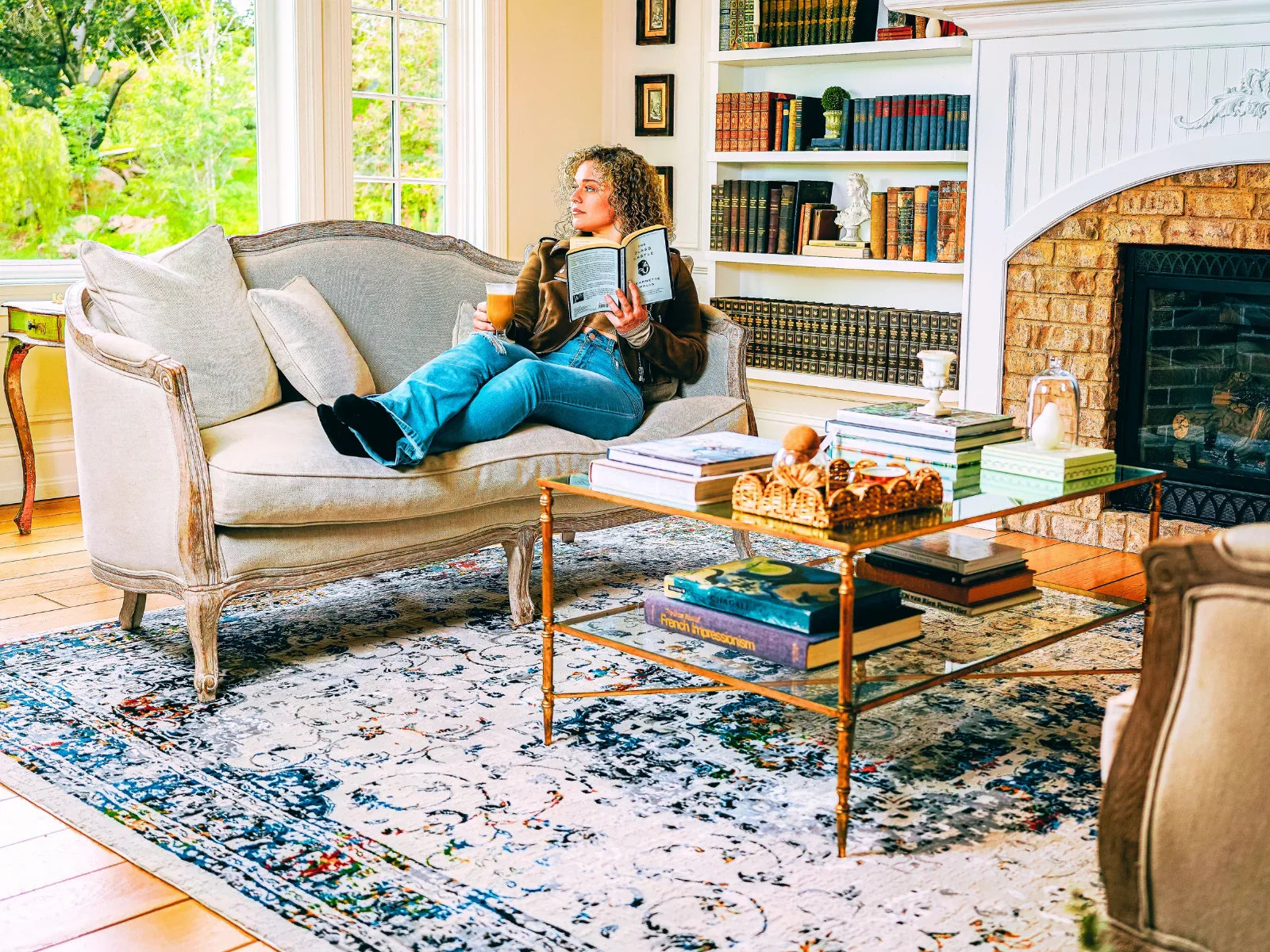 Cozy living room with blue patterned Turkish area rug, glass coffee table, and sofa by fireplace