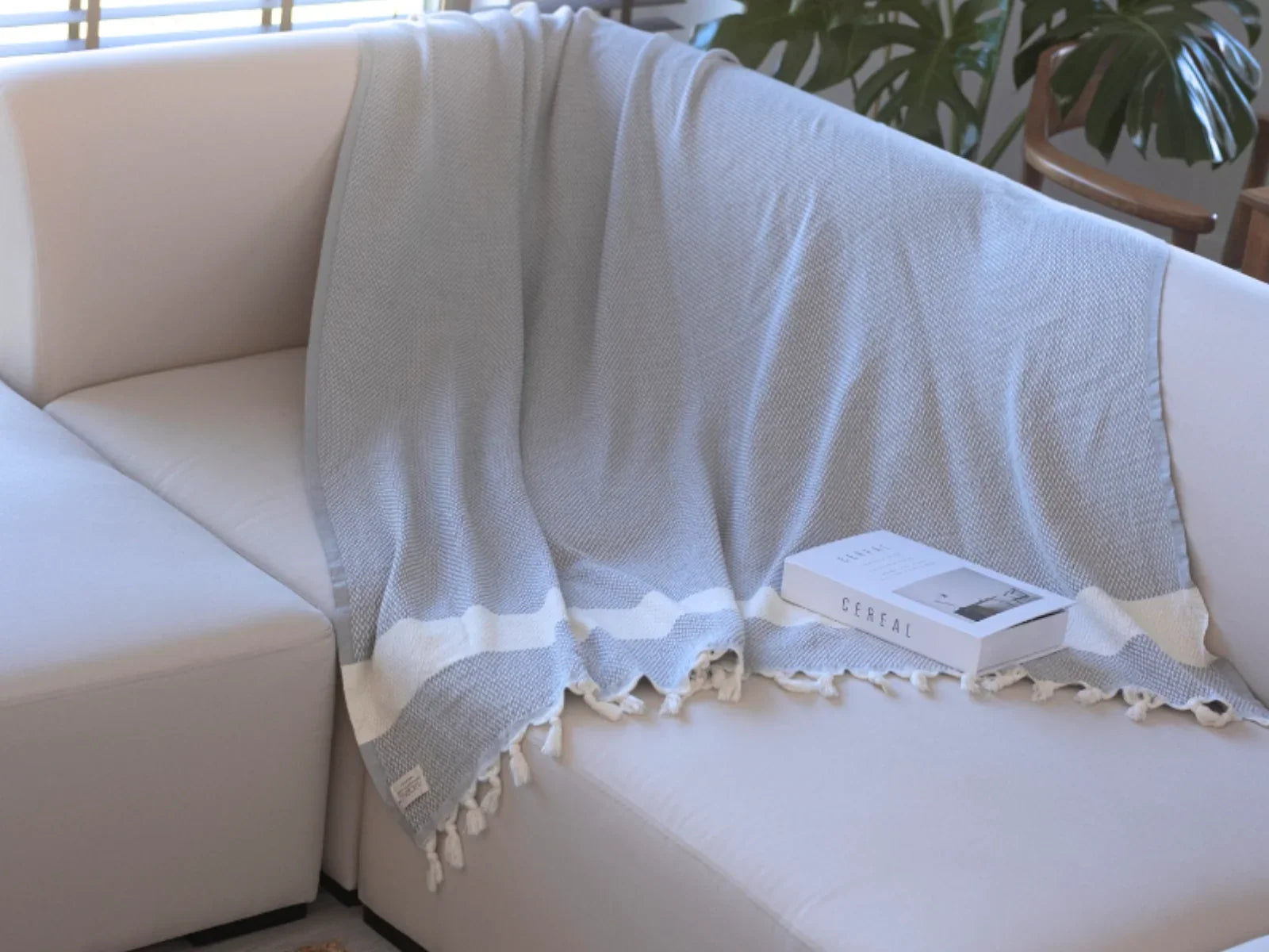 Light blue Turkish cotton throw blanket with white stripes draped over a cream sofa