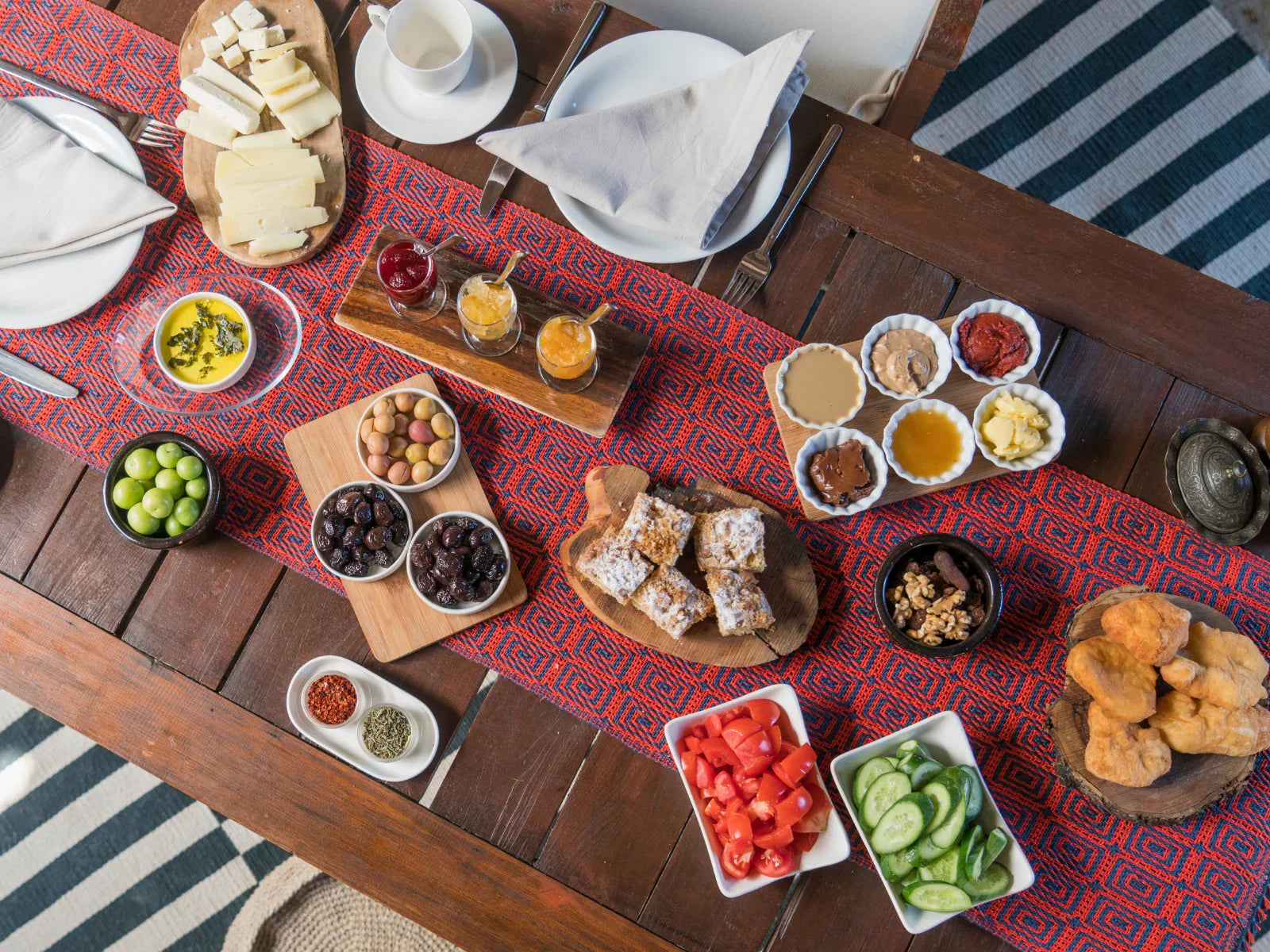 Traditional Turkish breakfast spread with cheeses, olives, jams, honey, vegetables, and pastries on a wooden table.