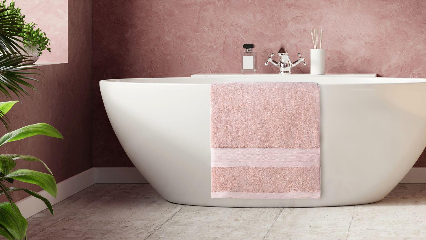Soft pink Turkish cotton towel draped on a white bathtub in a modern bathroom