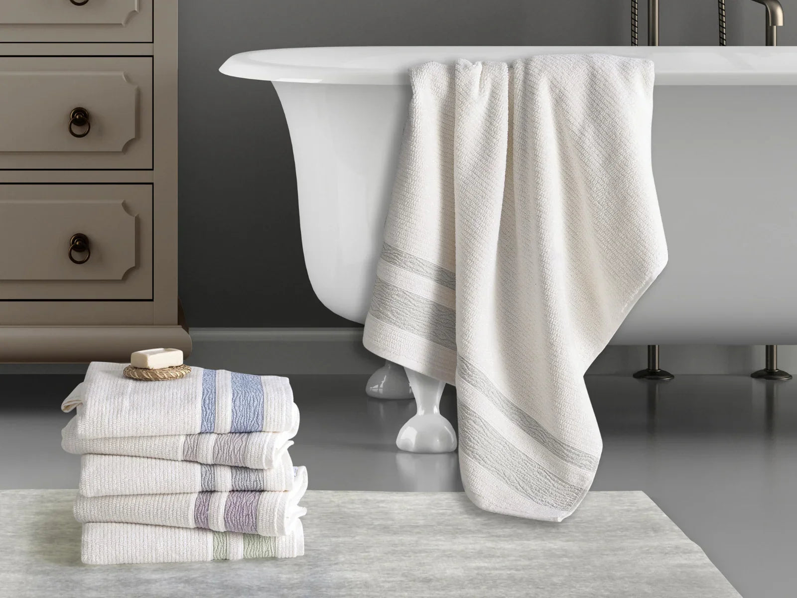 Stack of ribbed Turkish cotton towels and a towel draped on a bathtub in a modern bathroom