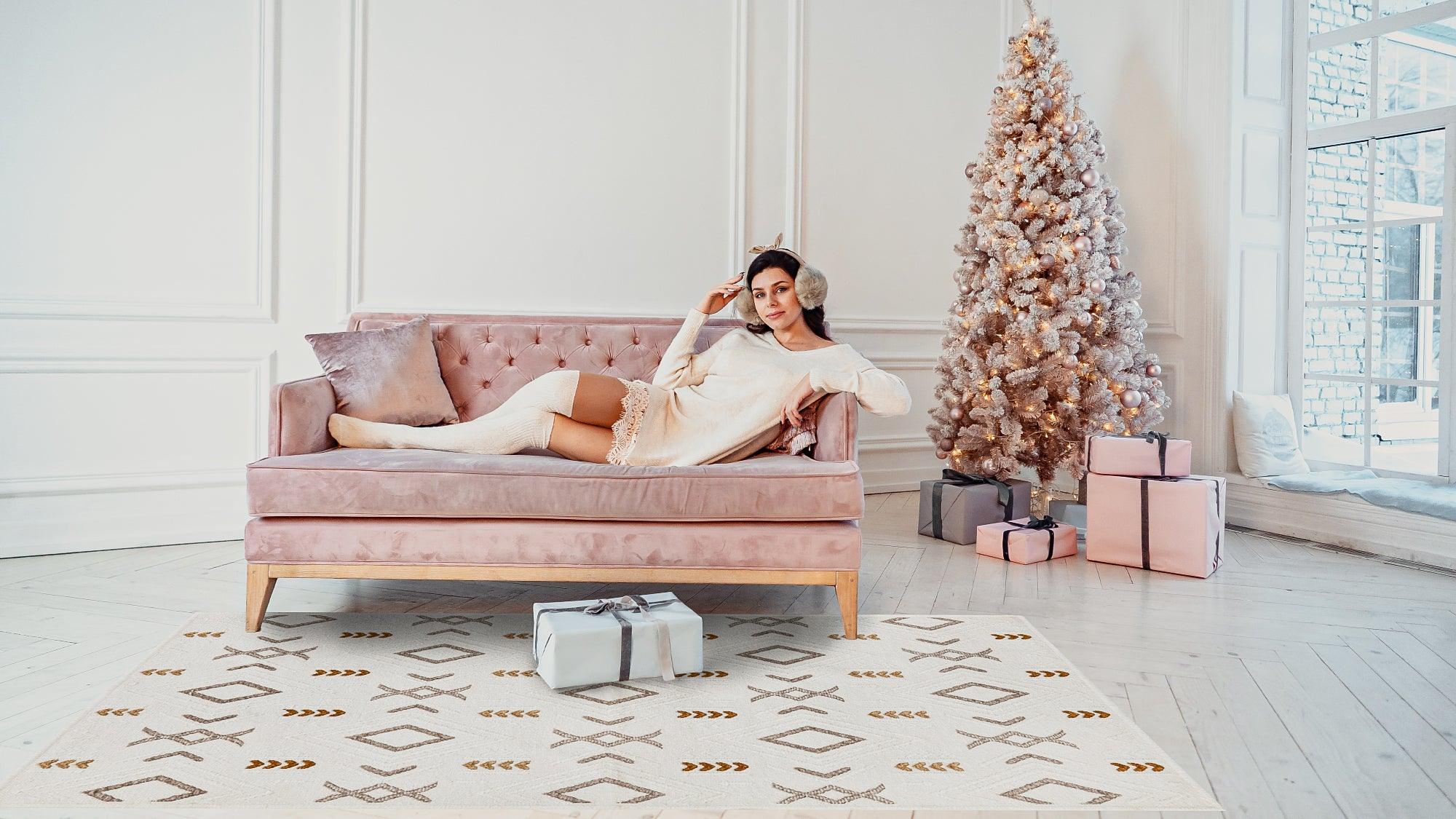 Cozy living room with pink sofa, woman relaxing, festive Christmas tree, and patterned area rug