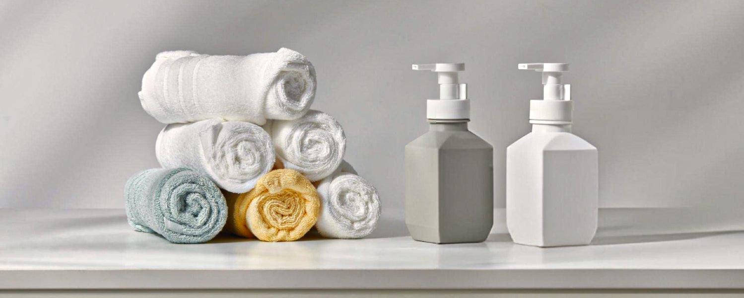 Rolled Turkish cotton towels and soap dispensers on a white bathroom counter
