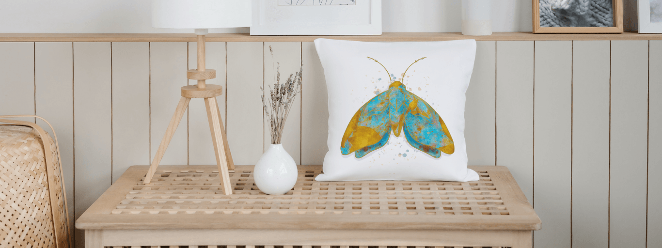 Stylish cotton pillow cover with vibrant moth design on a wooden bench, featuring sustainable materials and home decor elements.