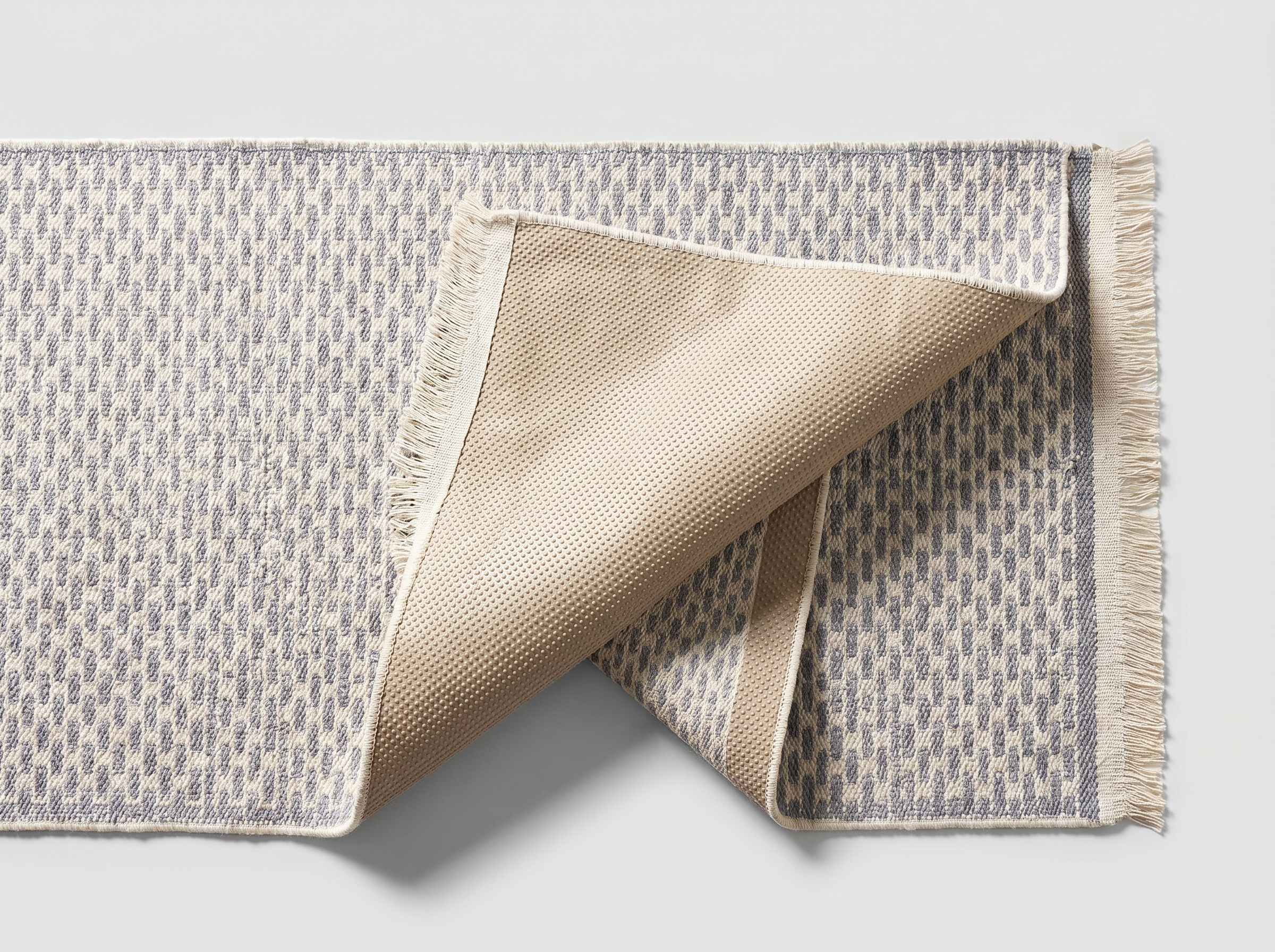 Underside of the light gray runner rug showing the silicone non-slip backing