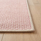 Close-up of the bound edge and low pile of the pink geometric check runner rug