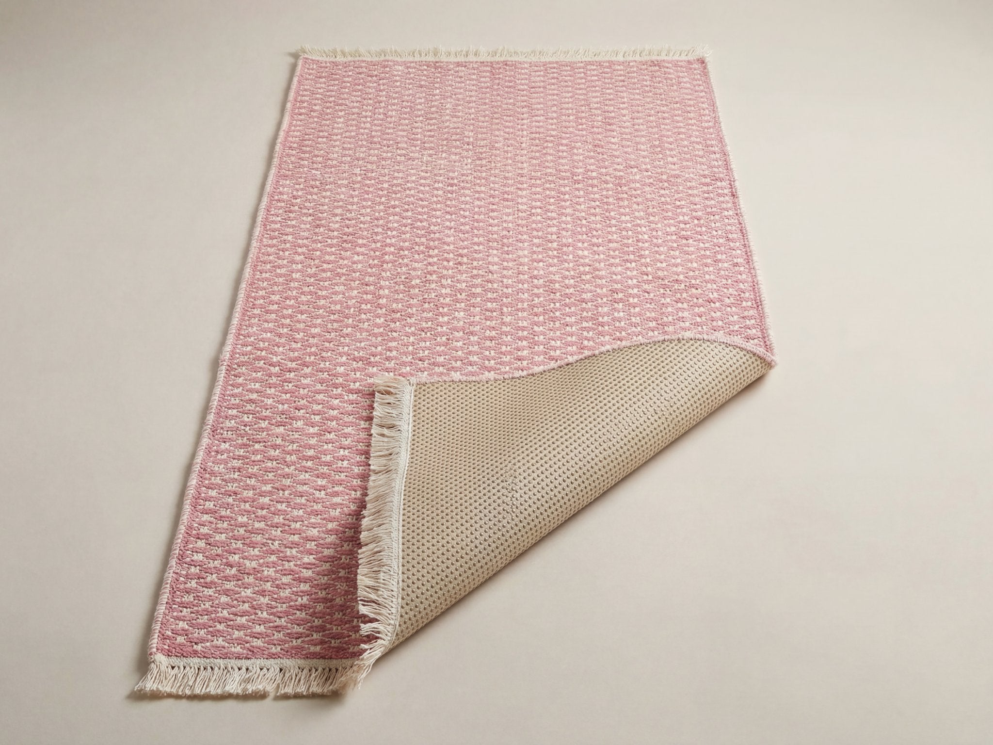 Underside of the pink runner rug showing the silicone non-slip backing