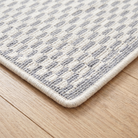 Close-up of the bound edge and low pile of the light gray geometric check runner rug