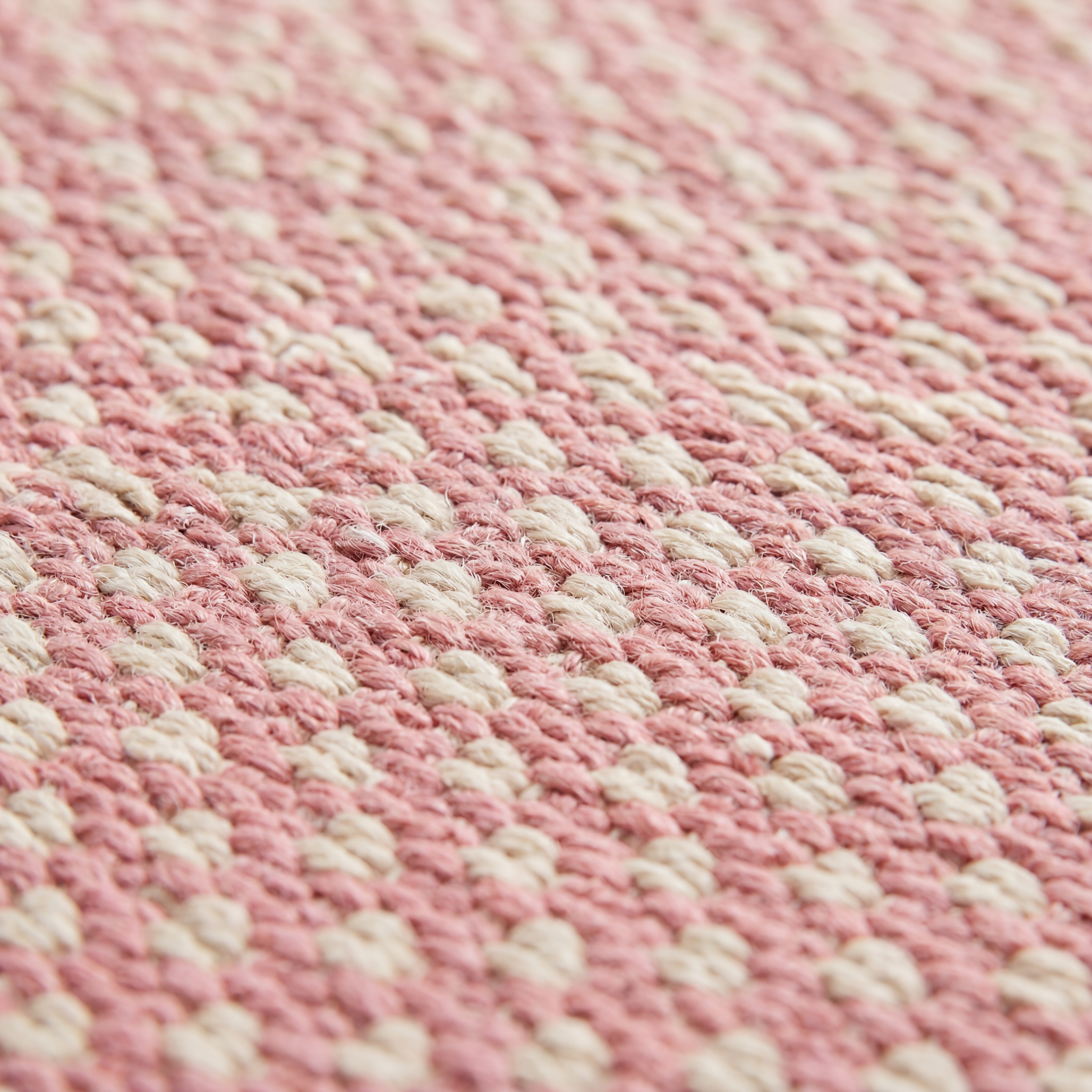 Close-up of the flat-woven kilim weave texture of the pink geometric check rug